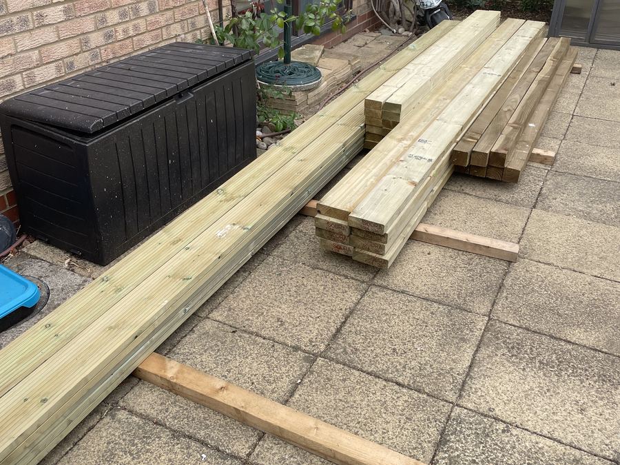 Lengths of structural timber delivered and stacked on a patio ready for a pergola build