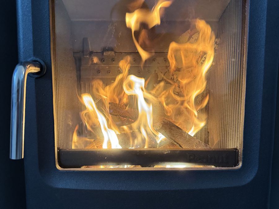 Close view of flames behind the glass door of a blue enamel woodburning stove